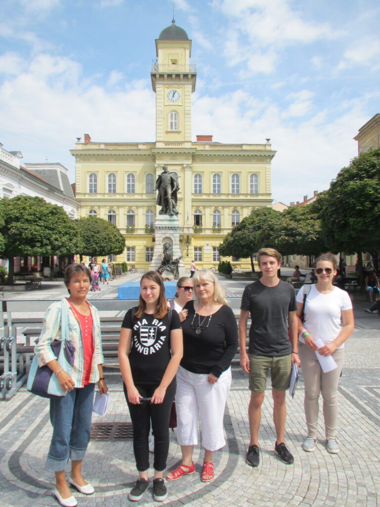 Tanárok és diákok csoportképe egy tanulmányi kiránduláson, egy városháza előtti téren